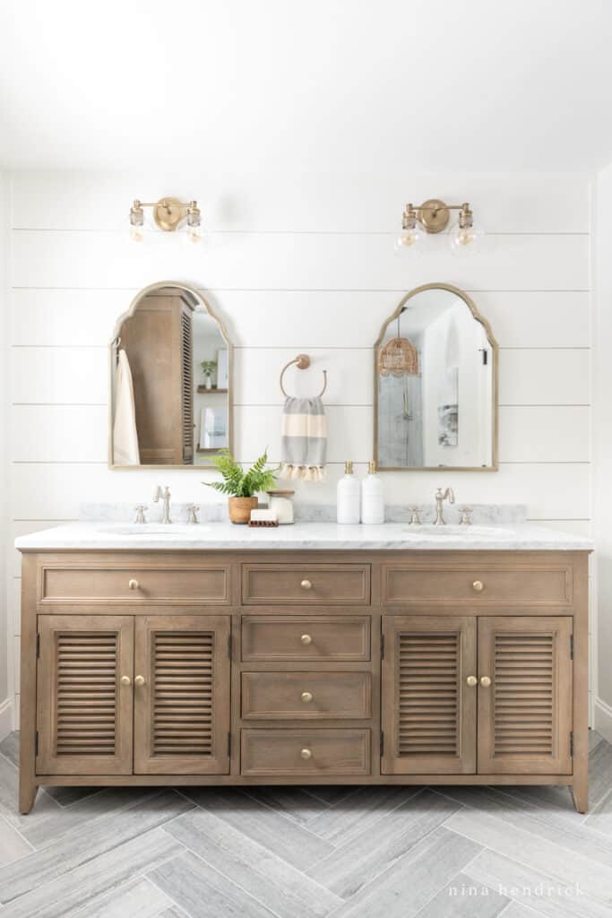 Natural wood bathroom vanity with PVC shiplap wall and gold mirrors