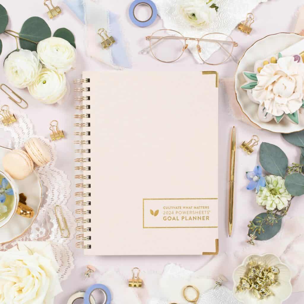 A wedding planner utilizing goal planning tools on a table with flowers and other items.