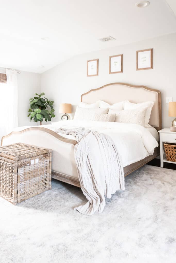 Primary bedroom makeover with neutral gray and white rug with a wood and upholstered bed.