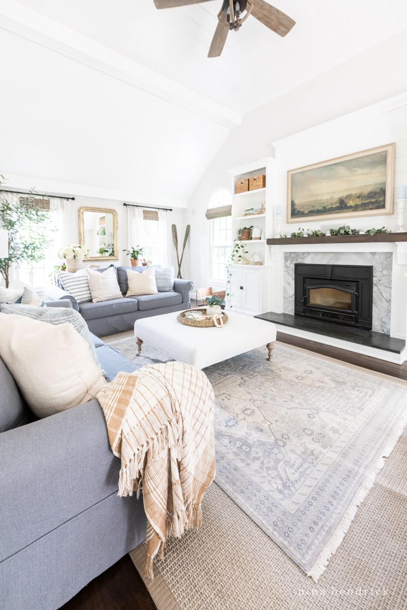 Layering rugs in a living room with a custom rug size and a 6x9' decorative rug on top.