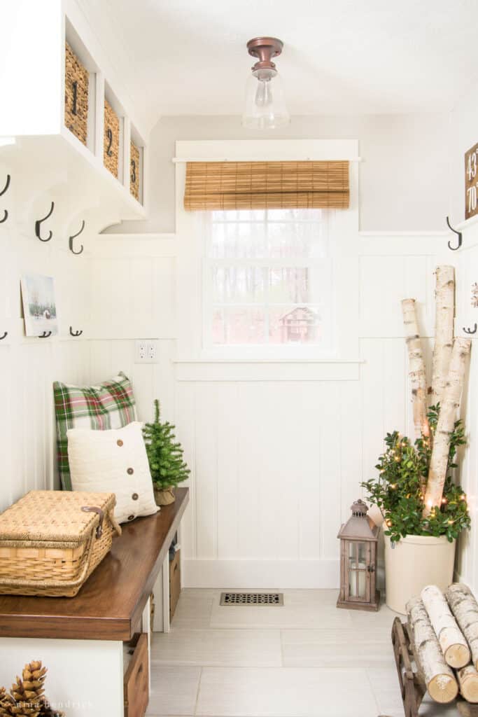 Mudroom decorated for Christmas with birch logs and plaid throw pillows. 