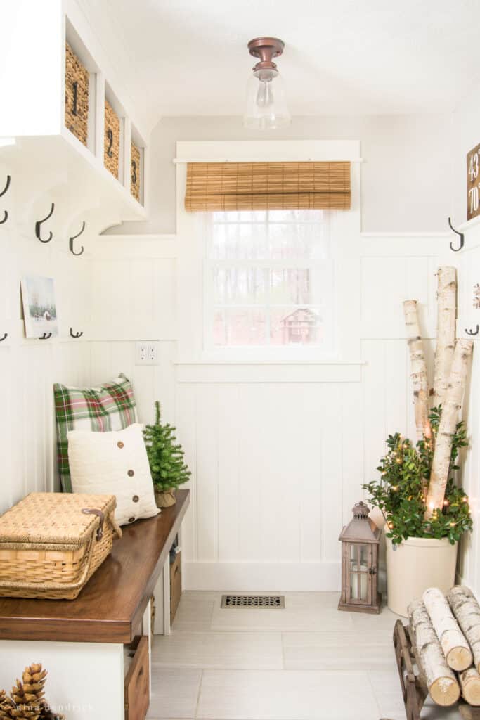 Mudroom decorated for Christmas with birch logs and plaid throw pillows.