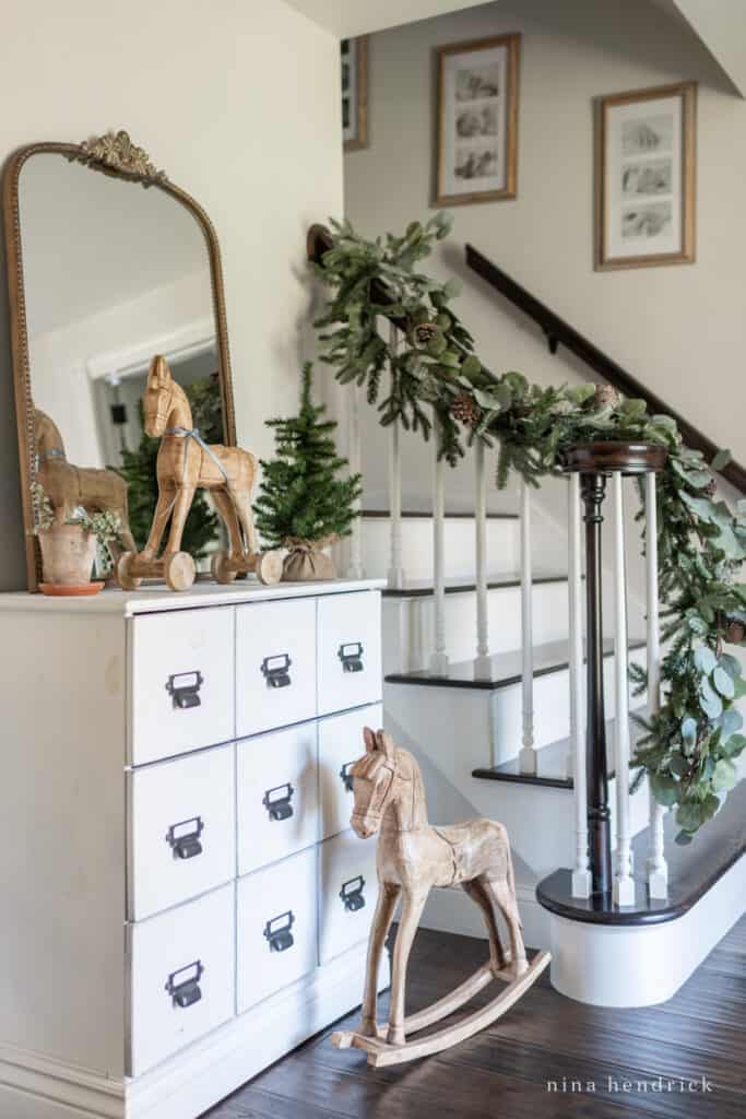 Christmas decorations in the foyer with a garland wrapped around the stiar railing