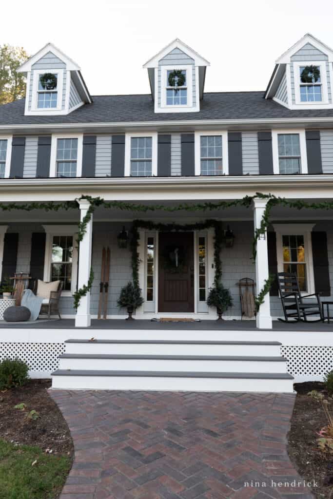 Front stairs and brick walkway leading up to a blue colonial decorated for Christmas