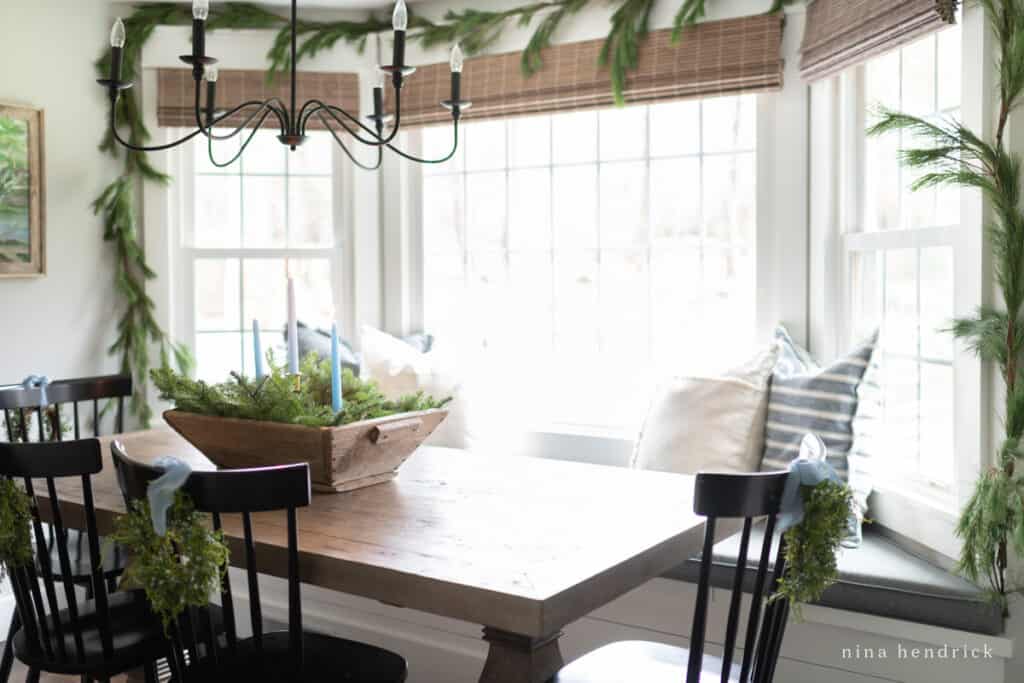 Blue Christmas accents on chairs with a wooden table and garland