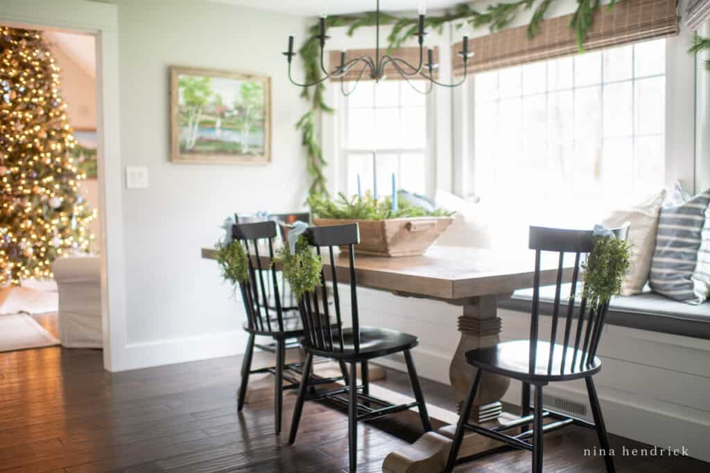 Blue Christmas decorations in the breakfast nook with bue candles and pillows and blue ribbons hanging juniper wreaths