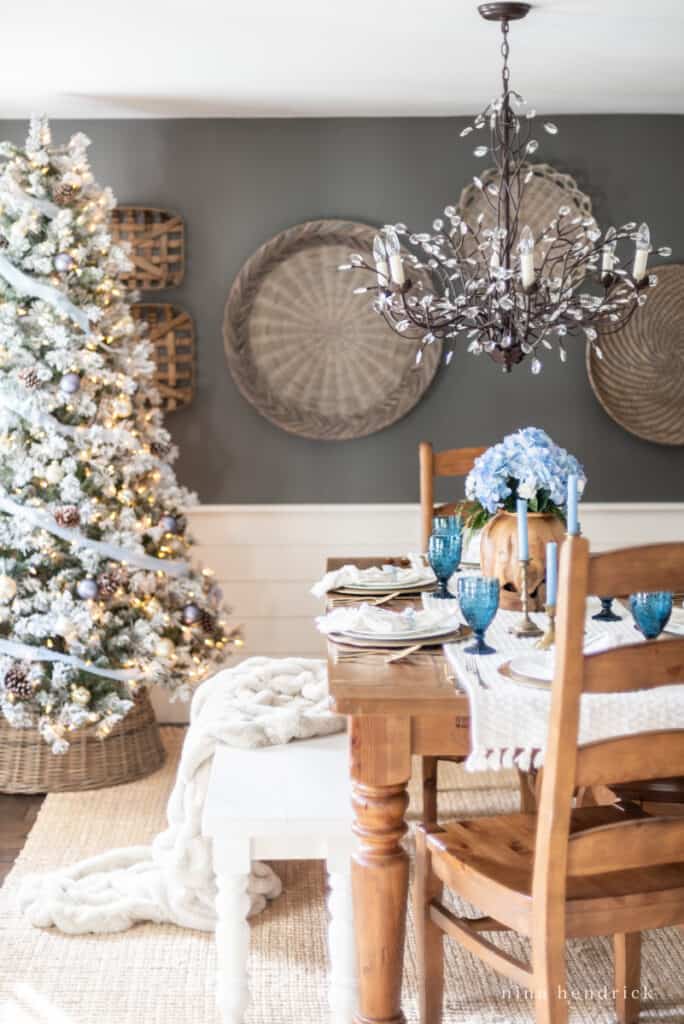 Dining room with warm wood table and blue hydrangeas with a Christmas tree in the background