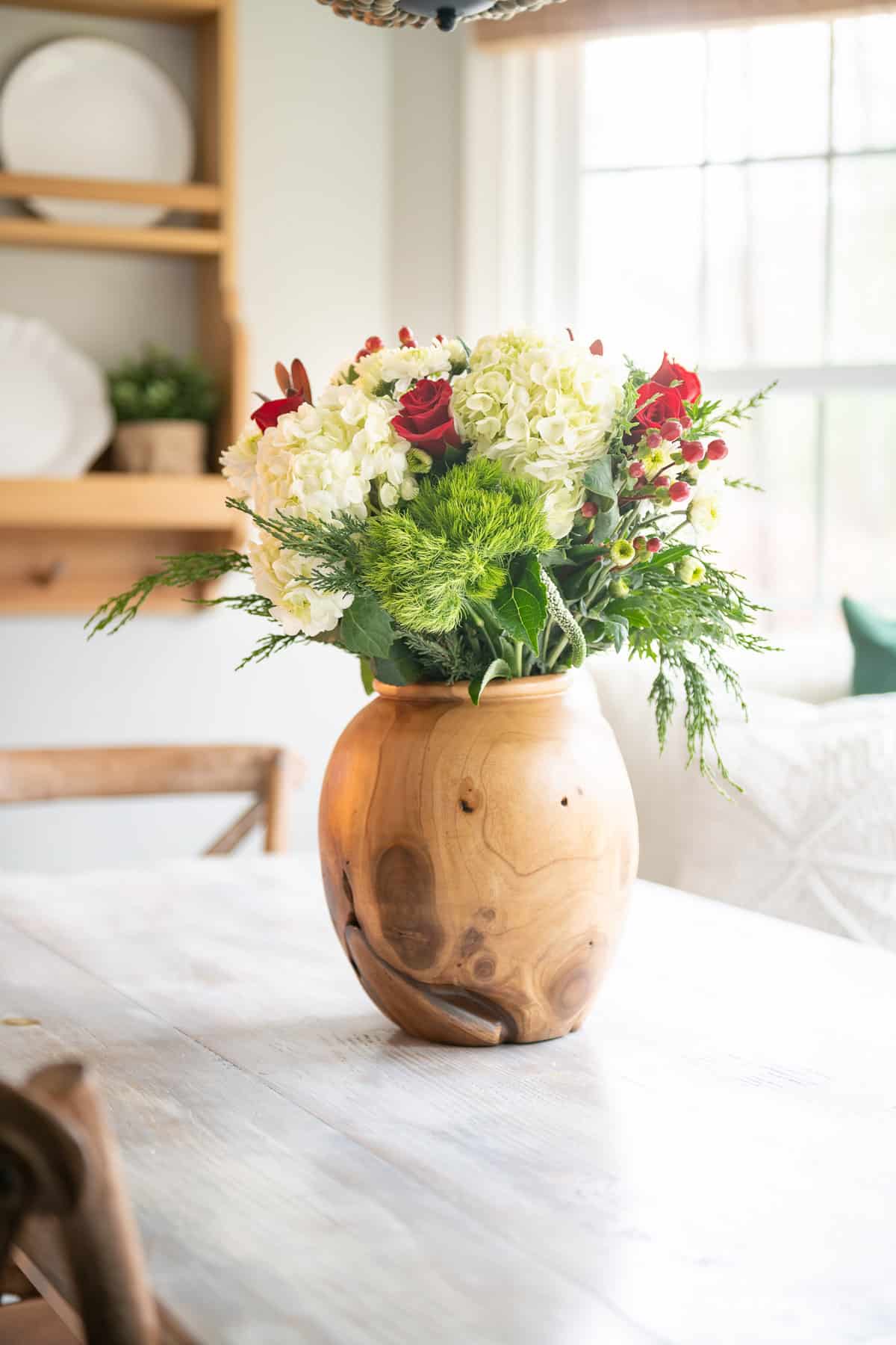 Christmas floral arrangment with red, white and green flowers in a wooden vase