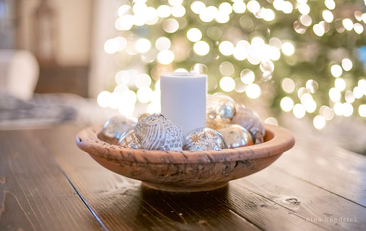 Wooden bowl filled with ornaments in front of tree lights