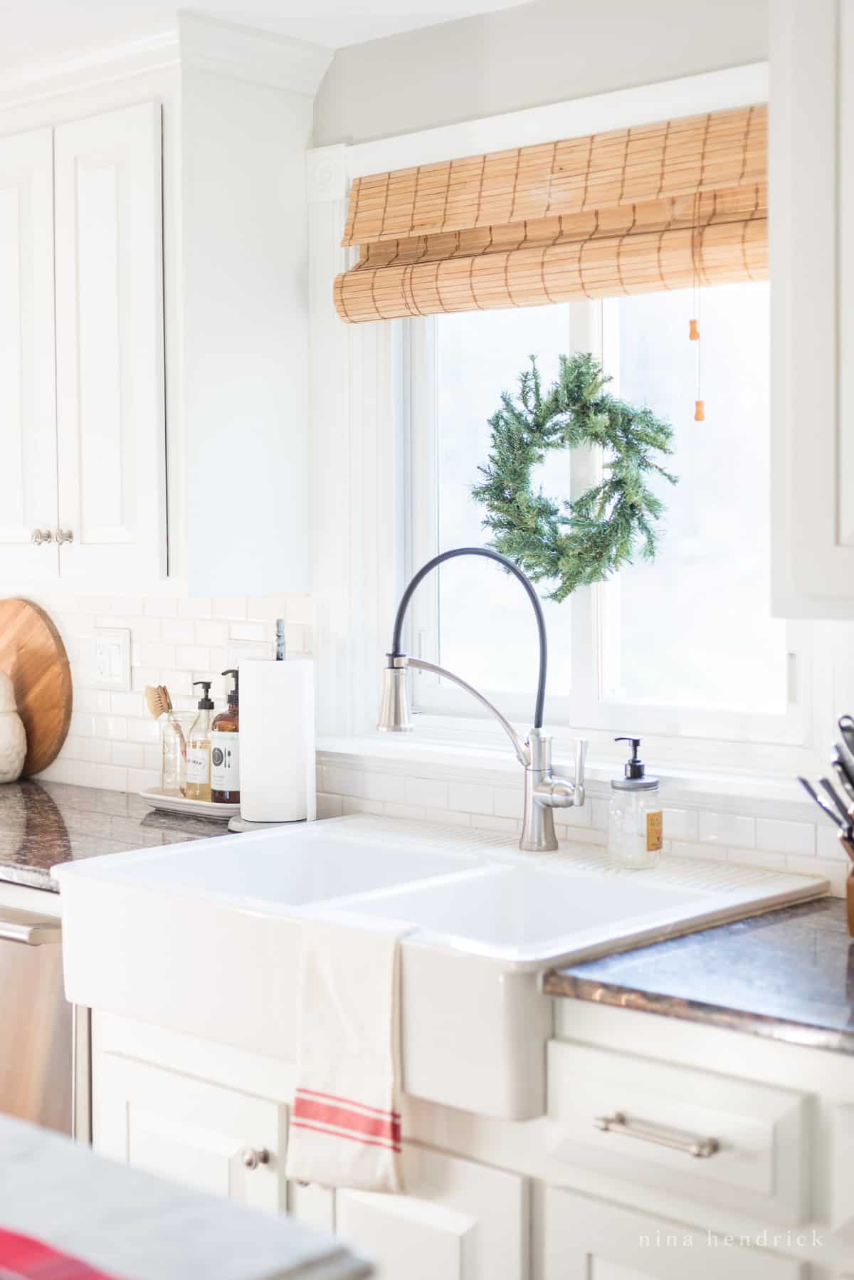 Kitchen sink with a red striped towel and an evergreen wreath above