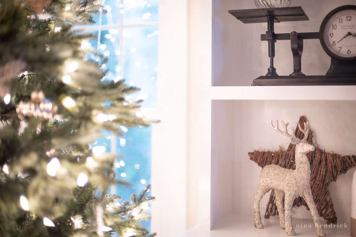 Simple Christmas decor — a glitter deer figurine and a star on a shelf beside the Christmas tree