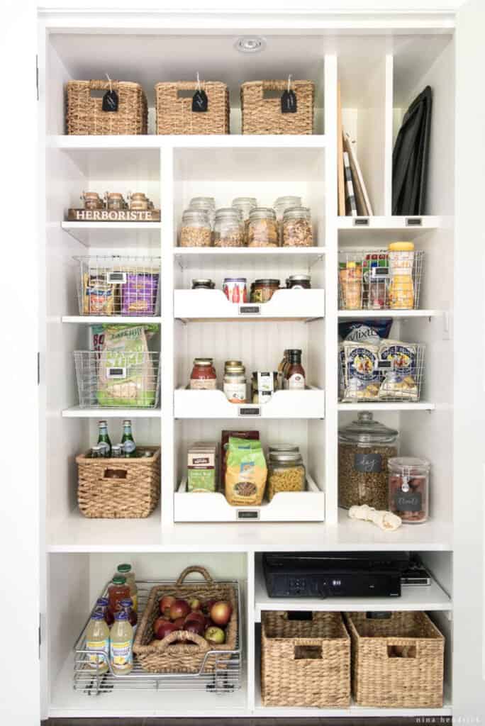 Small organized pantry with wicker baskets and glass jars.