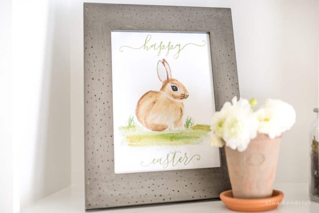 Happy Easter framed printable on a shelf with a flowerpot