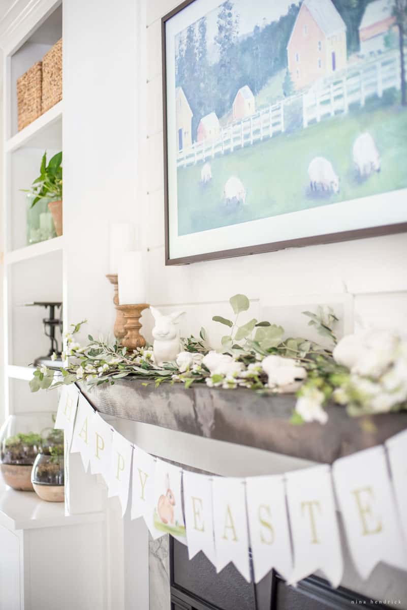 A simple and fresh spring mantel with blossoms, Easter bunny decor, and a banner.