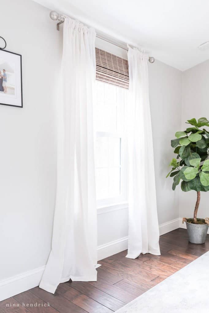 white curtains hanging in white room with roman shade attached to window