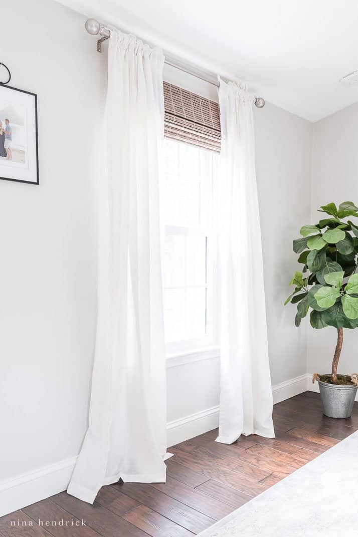 white window treatments hanging in white room with an inexpensive roman shade attached to window