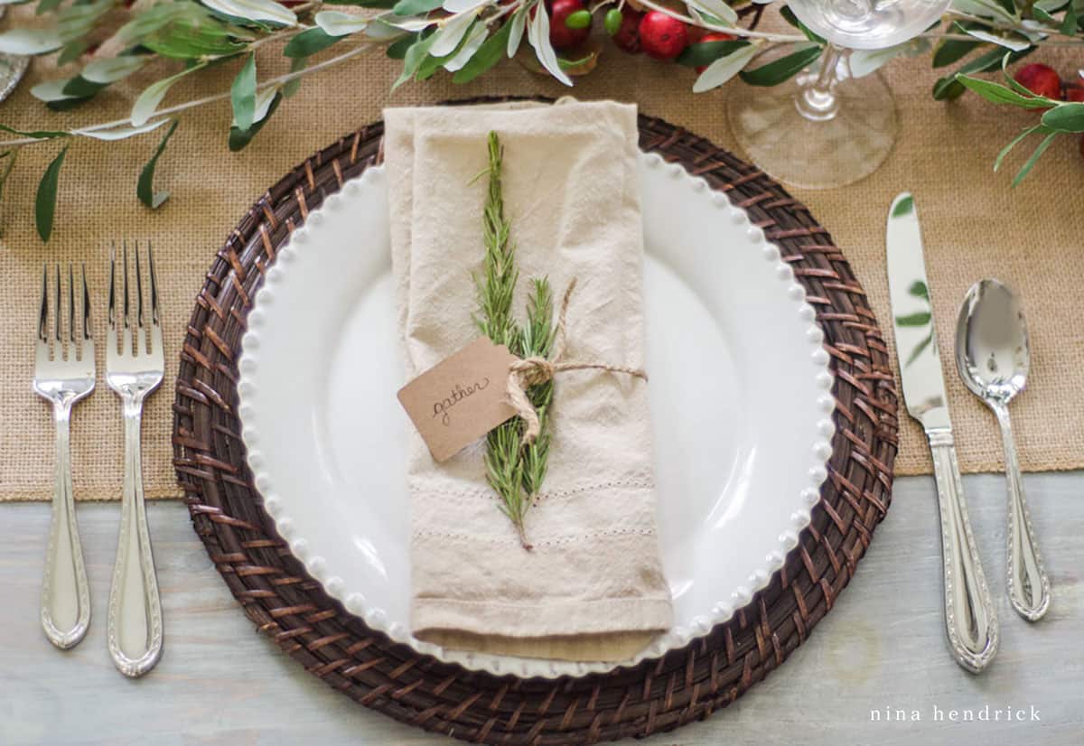 A Thanksgiving place setting with greenery and silverware.