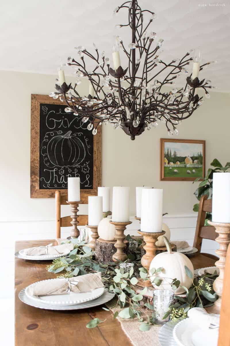 A Thanksgiving dining room table with a chalkboard and pumpkins.