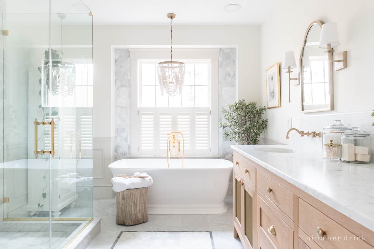 Timeless primary bathroom remodel with white marble, warm white oak and brass accents.