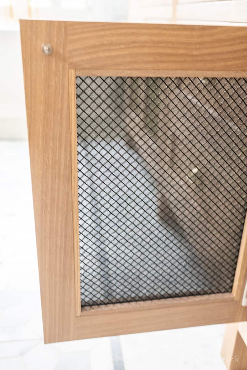 Black semi-transparent speaker fabric on the back of a mesh door panel.