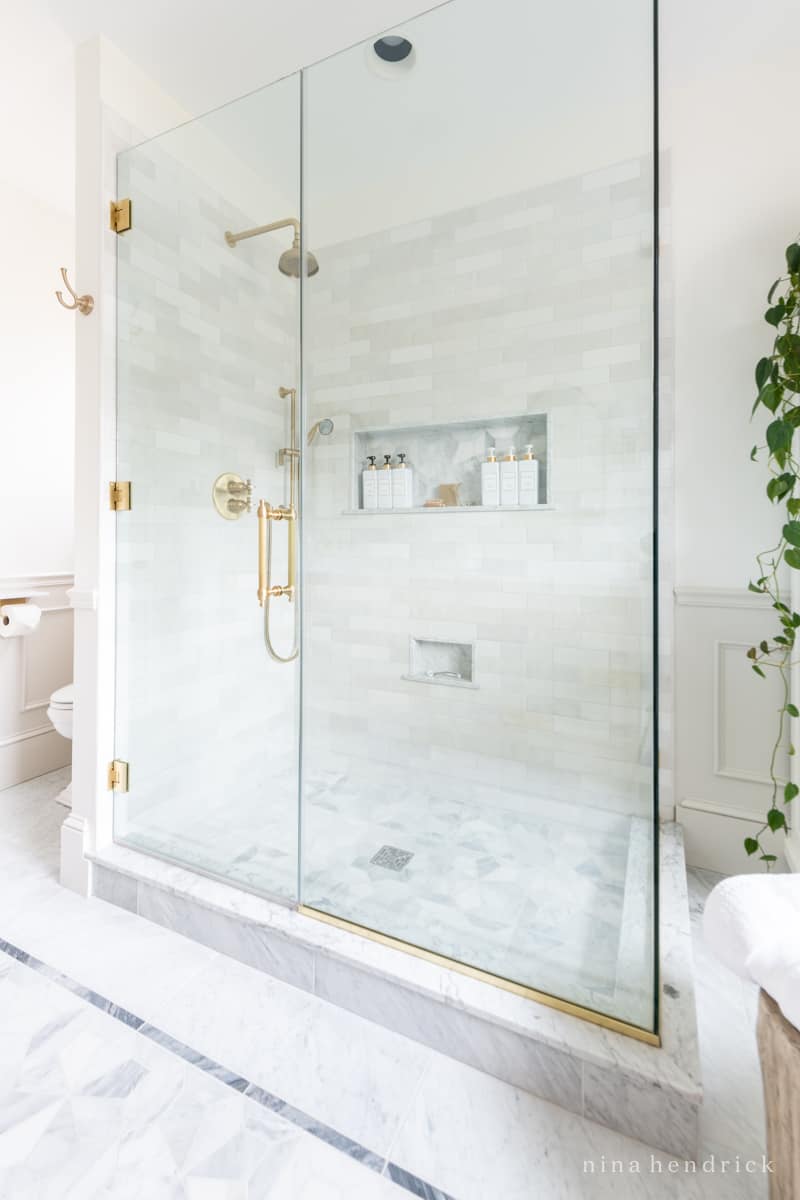 Bathroom remodel shower enclosure with marble tile and brass accents