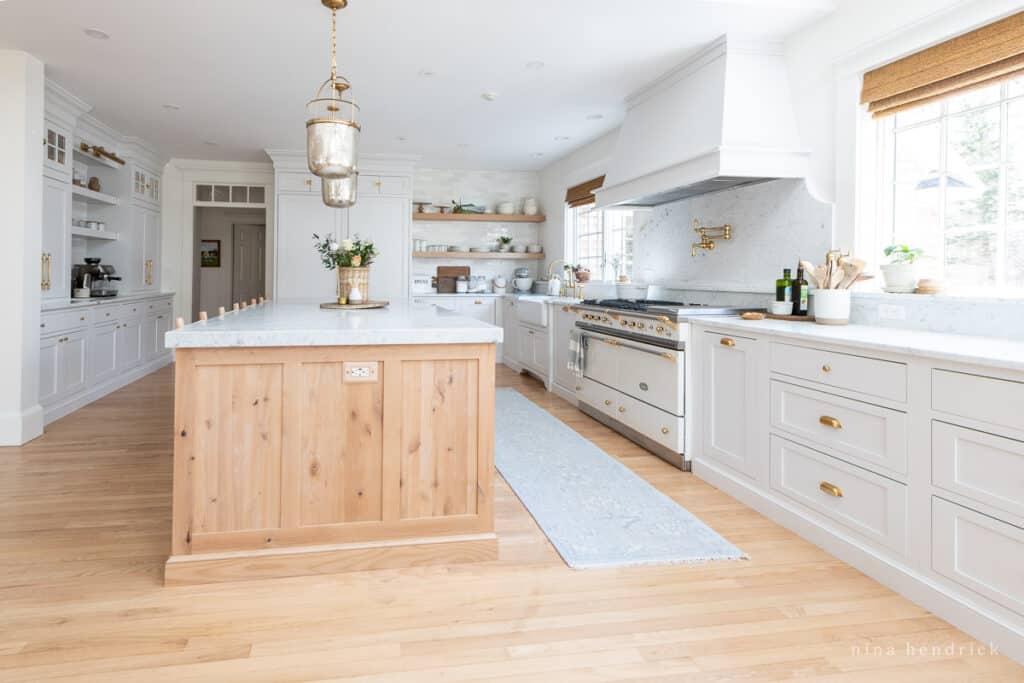 Kitchen with wood island and white cabinets with brass hardware