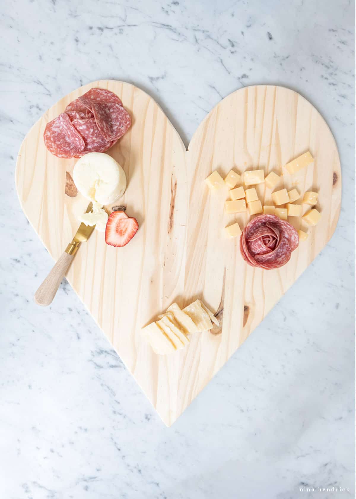Adding salami roses to a cheese board