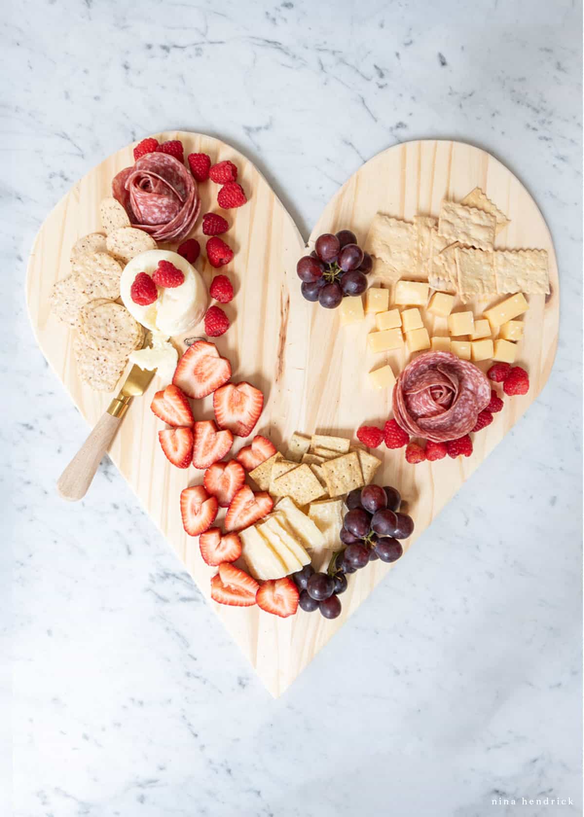 Heart-shaped snack platter with fruit, meat, cheese and crackers