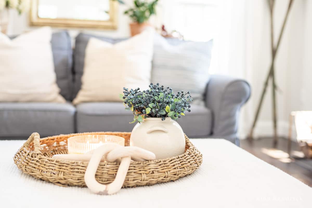 Wicker tray with wooden links and a vase of berry picks