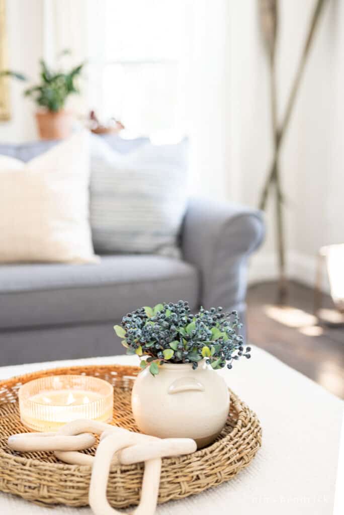 Decor vignette with wicker tray, wooden links, candle, and a vase with blueberries