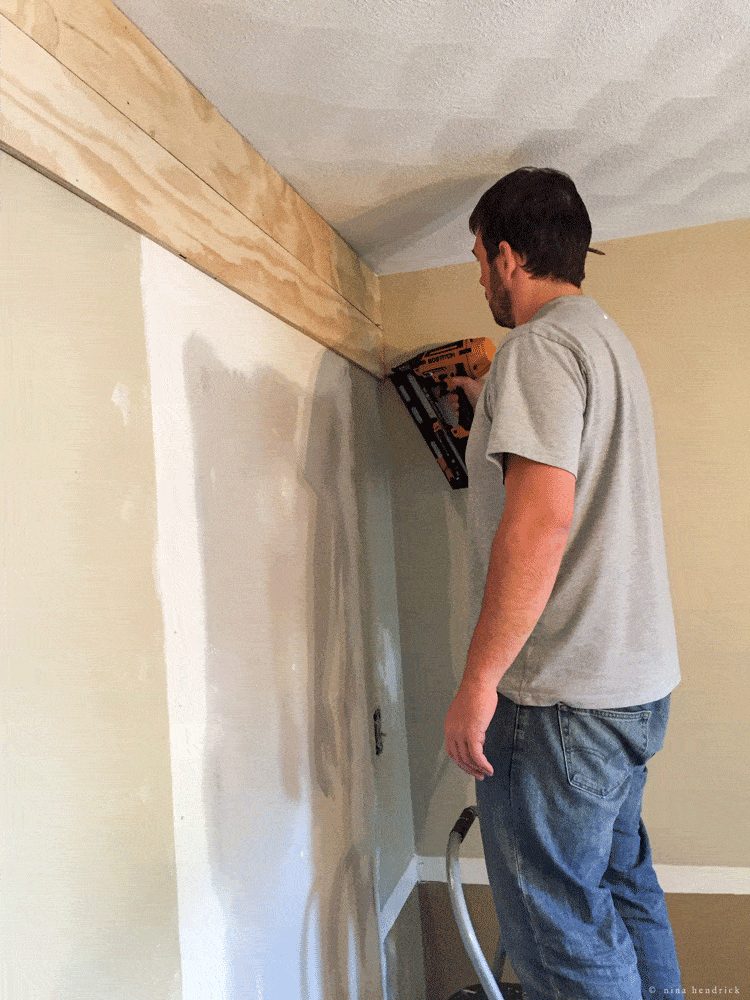 Using a nail gun to secure planks to wall