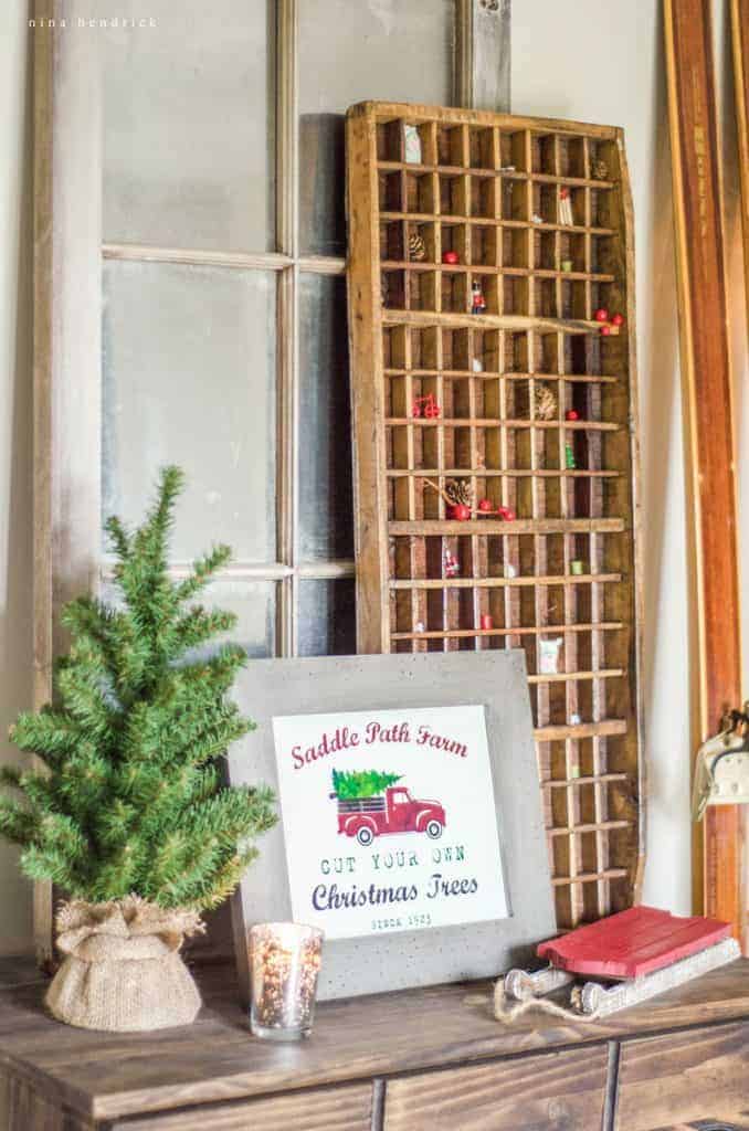 Cozy Christmas vignette featuring a framed printable tree farm sign, printer's tray, and vintage skis