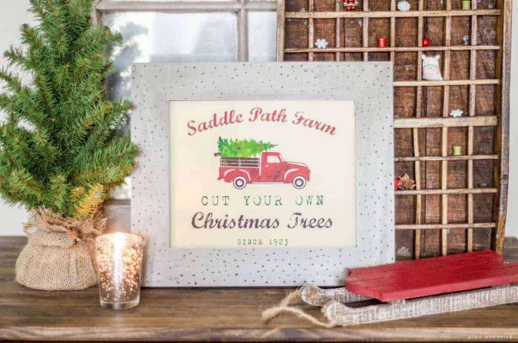 Printable tree farm sign in a rustic frame with tabletop tree and a red sled with a printer's tray. 