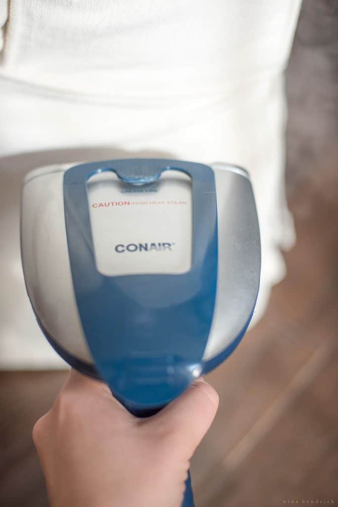 using handheld fabric steamer to smooth white slipcovers