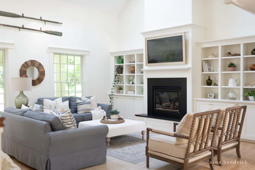 white family room with gray slipcovers with a wooden round mirror and fireplace built-ins