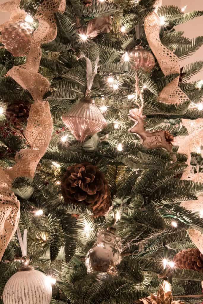 pinecones, mercury ornaments, and lace on a glowing christmas tree
