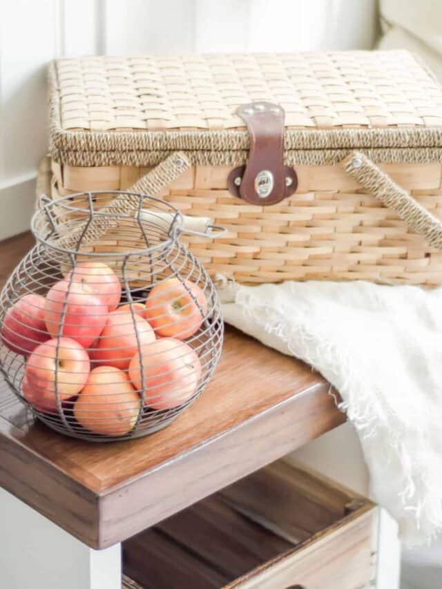A wicker basket filled with apples on a wooden table.