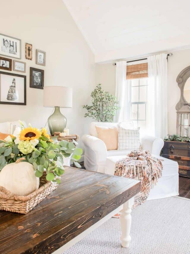 A living room with white furniture and a wooden table.