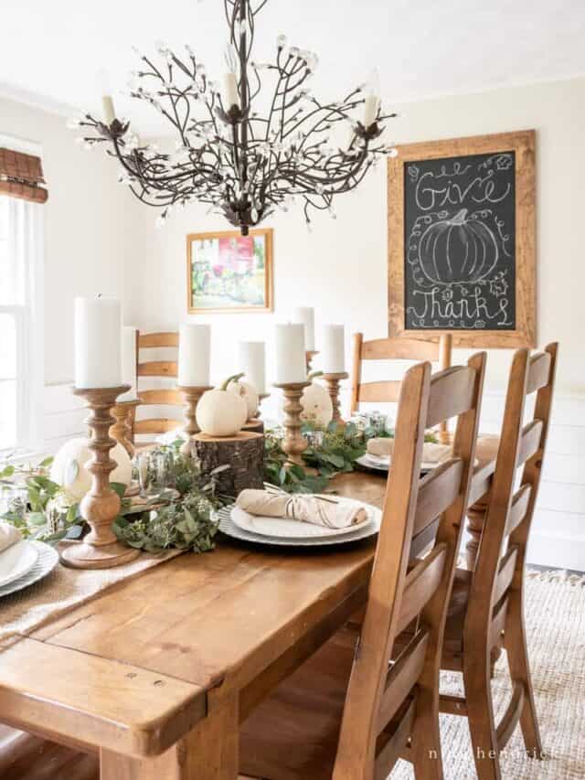 A dining room with a wooden table and chairs and a chalkboard.